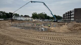 Crew pours concrete using boom pump at Chapel View building site.